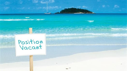 Photo of a beach with the sign saying "position vacant"