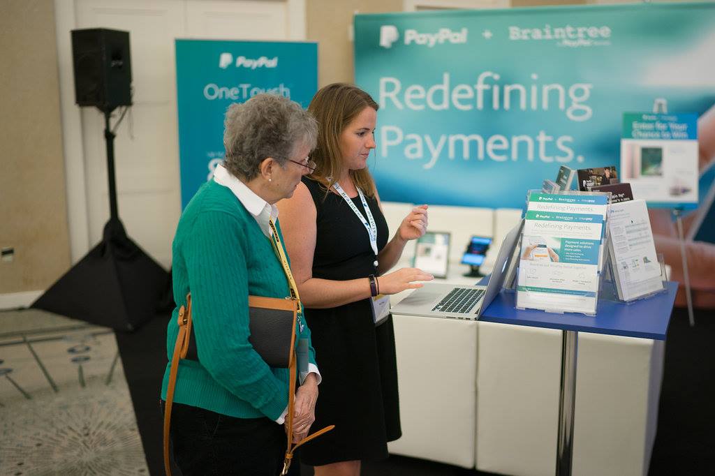 Two women talking at PayPal tradeshow booth.