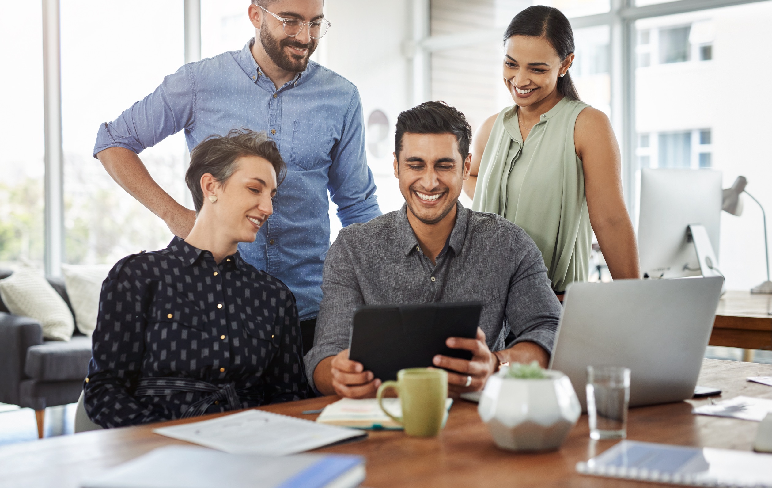 Young people working in office smiling at tablet