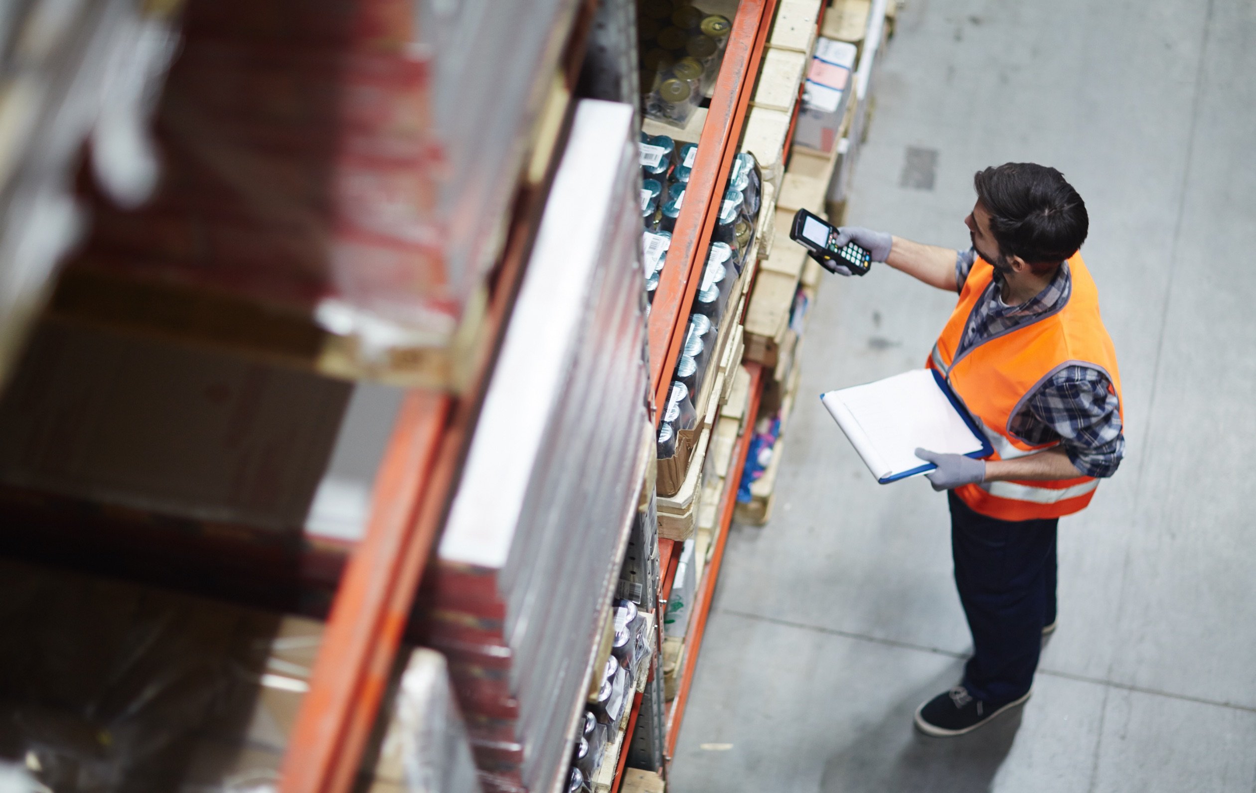 High angle photo of man inspecting inventory shelf in a warehouse.