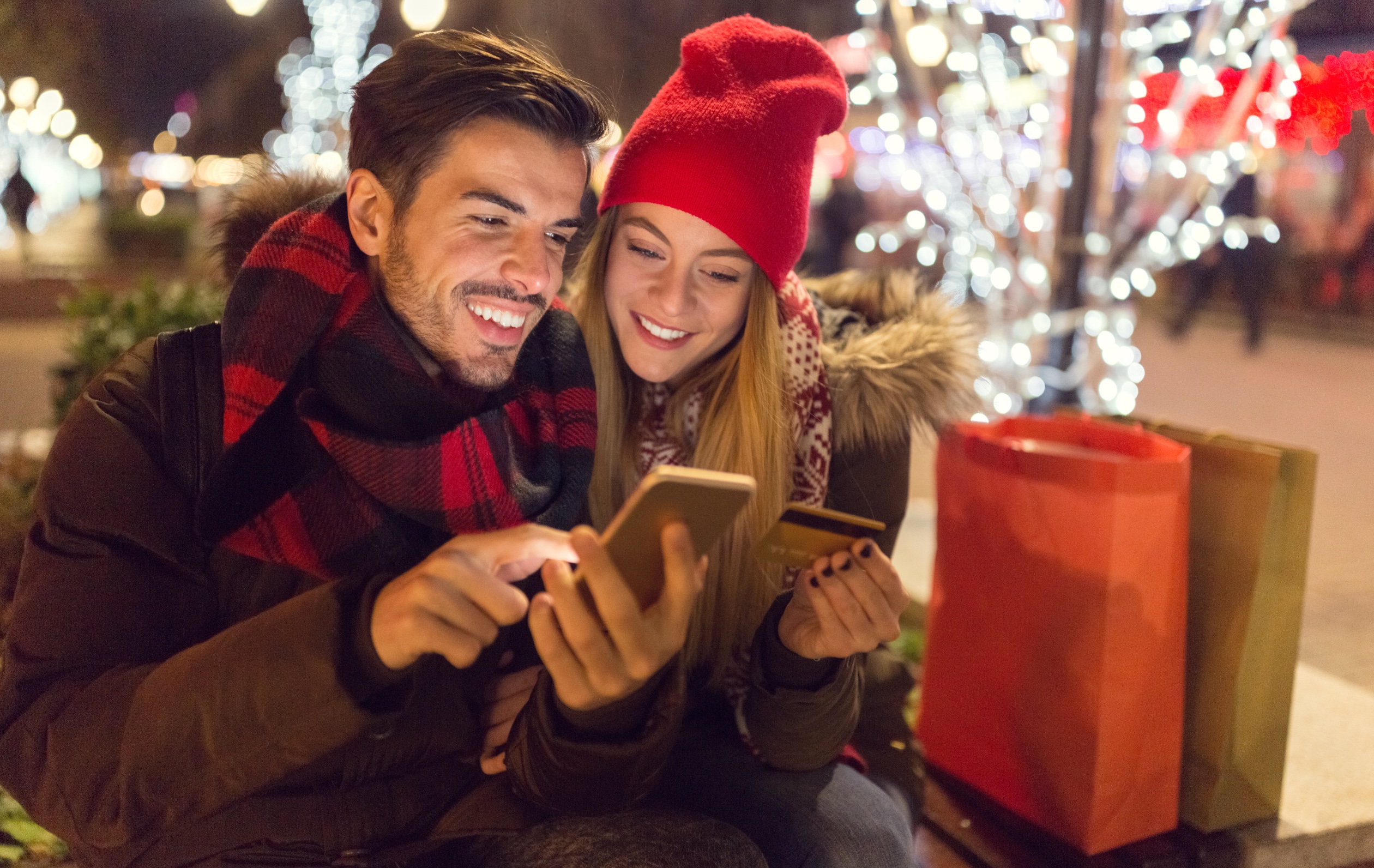 a smiling couple looking at a phone together during the holidays